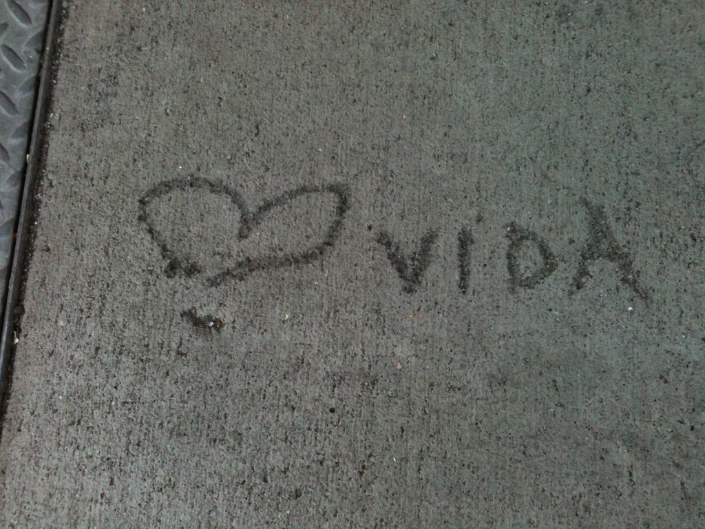 a heart scratched into concrete, next to the word 'vida'