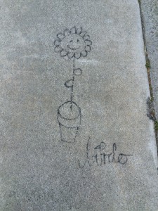 graffiti on cement sidewalk of smiling daisy growing out of a pot